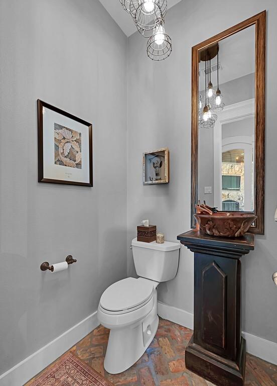 8416 Spicewood Springs Rd, Waco, TX 76633 - half bath featuring baseboards, toilet, a chandelier, and vaulted ceiling
