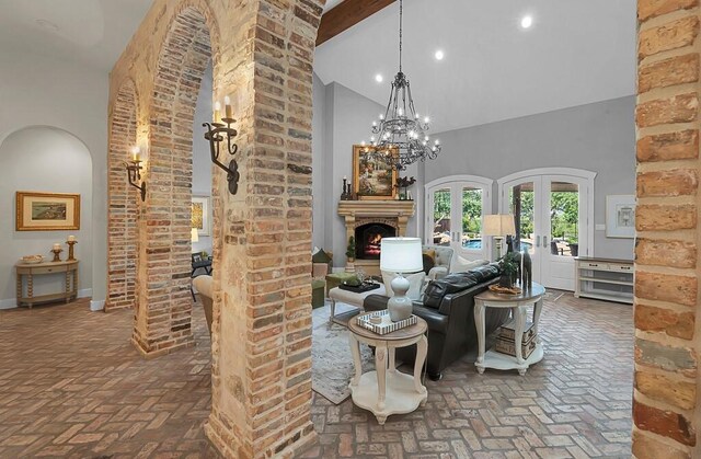 8416 Spicewood Springs Rd, Waco, TX 76633 - living room with high vaulted ceiling, brick floors, a chandelier, a lit fireplace, and arched walkways