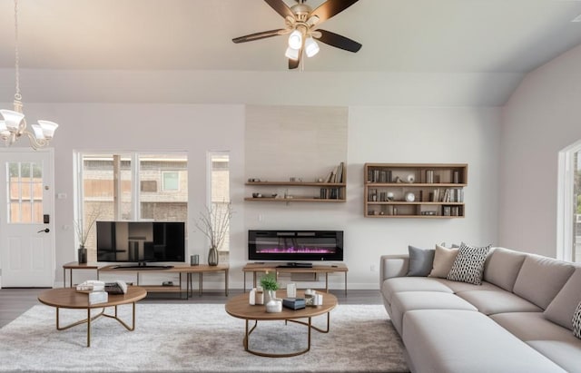 1435 Vine St, Weatherford, TX 76086 - living room with wood finished floors, a chandelier, a ceiling fan, a glass covered fireplace, and lofted ceiling