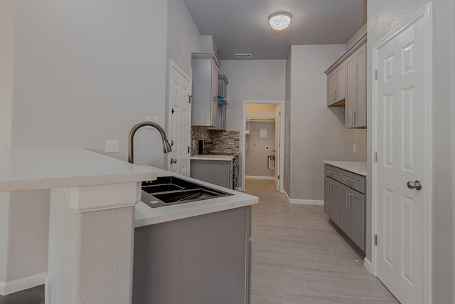 1435 Vine St, Weatherford, TX 76086 - kitchen with gray cabinetry, decorative backsplash, a peninsula, stainless steel range oven, and light countertops