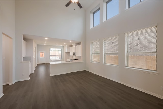 4118 Beale St, Heartland, TX 75114 - unfurnished living room featuring dark wood-style flooring, baseboards, ceiling fan, and a high ceiling