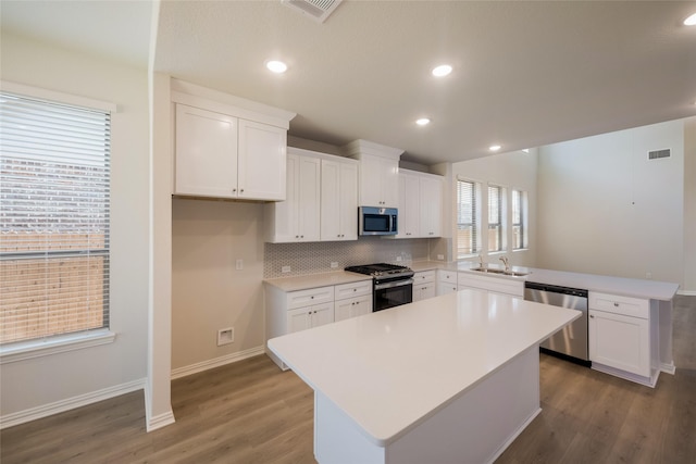 4118 Beale St, Heartland, TX 75114 - kitchen with appliances with stainless steel finishes, a peninsula, a sink, decorative backsplash, and wood finished floors