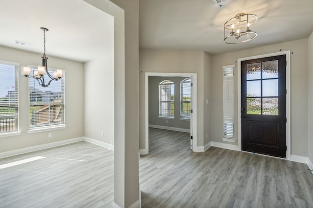 foyer entrance with a chandelier, wood finished floors, and baseboards