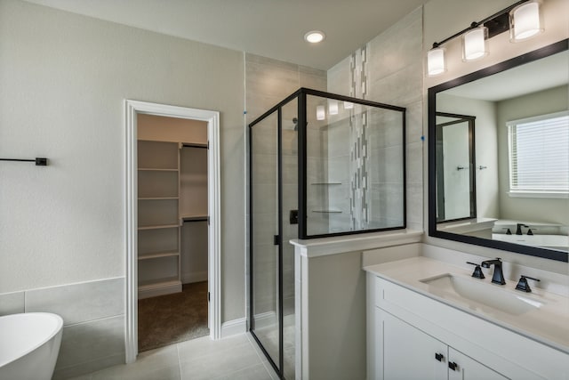 full bathroom with a stall shower, a soaking tub, a walk in closet, tile patterned floors, and vanity
