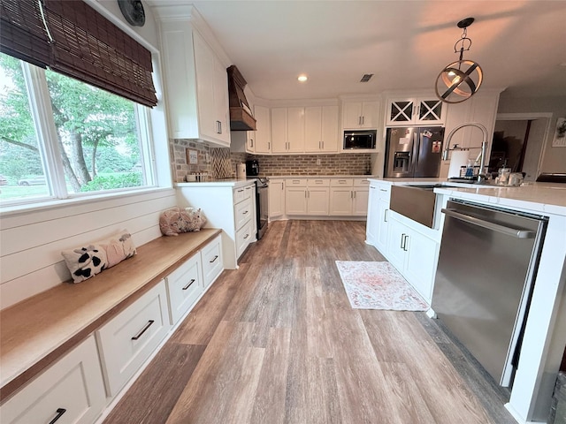 108 Martha Dr, Winnsboro, TX 75494 - kitchen with stainless steel appliances, light wood-style floors, premium range hood, light countertops, and pendant lighting