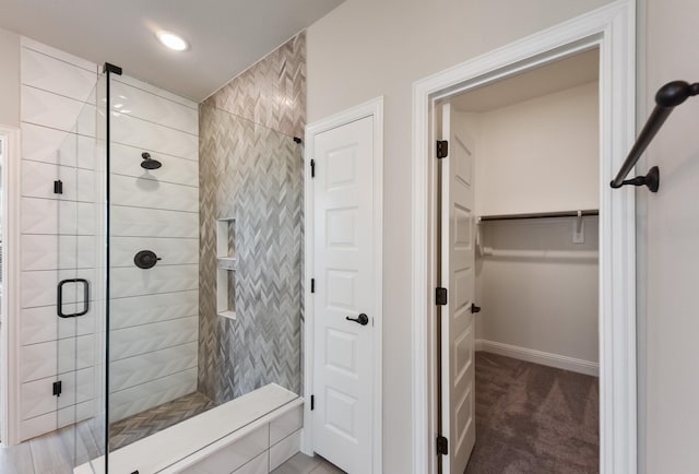 full bathroom with a shower stall, a spacious closet, and baseboards