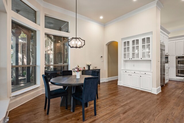 dining area featuring arched walkways, ornamental molding, a chandelier, dark wood-style flooring, and baseboards