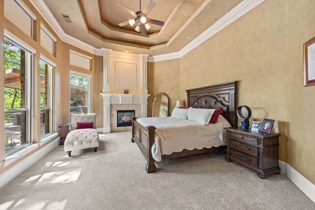 bedroom featuring light colored carpet, a tray ceiling, a tile fireplace, baseboards, and crown molding
