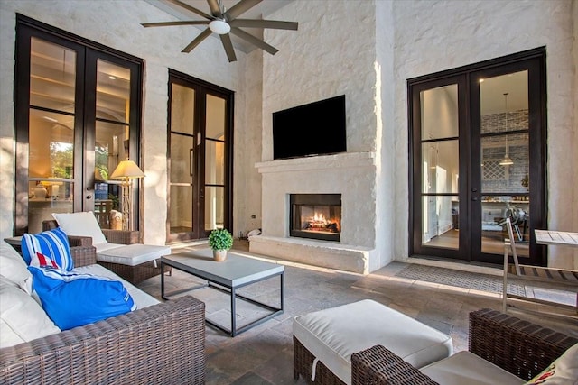 10031 Tumbling Trl, Waco, TX 76657 - living room with stone tile floors, a ceiling fan, a warm lit fireplace, and a towering ceiling