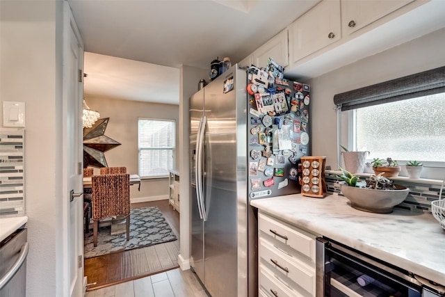3201 Elizabeth St, Dallas, TX 75204 - kitchen featuring freestanding refrigerator, white cabinetry, beverage cooler, light wood-style floors, and baseboards