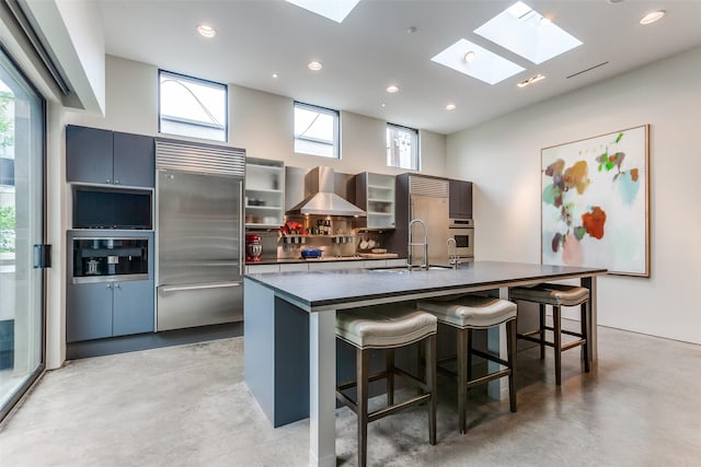 4335 Travis St, Dallas, TX 75205 - kitchen with stainless steel appliances, wall chimney range hood, dark countertops, concrete floors, and recessed lighting