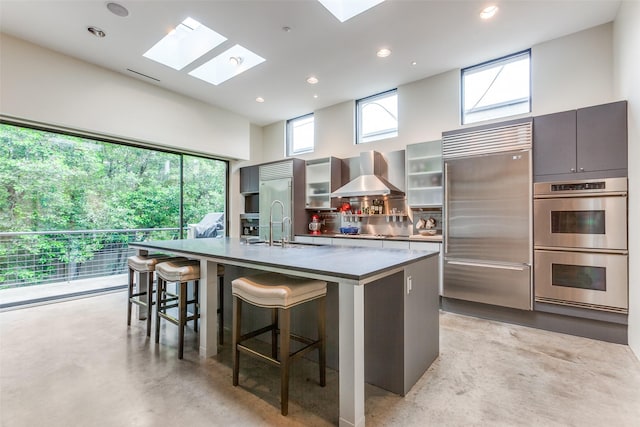 4335 Travis St, Dallas, TX 75205 - kitchen featuring appliances with stainless steel finishes, wall chimney exhaust hood, finished concrete floors, a large island, and a breakfast bar