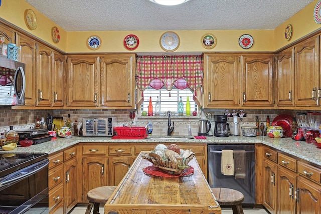 kitchen with dishwasher, stainless steel microwave, a sink, a textured ceiling, and brown cabinets