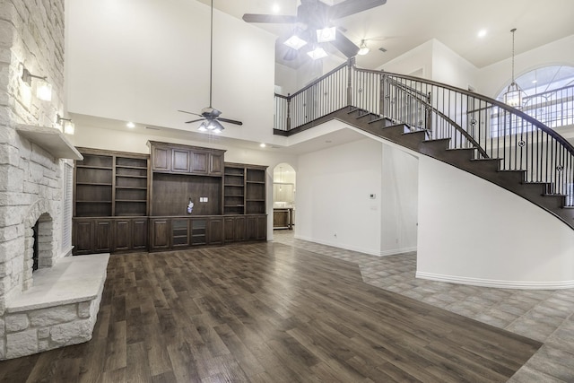 124 Fm 2450, Krum, TX 76249 - unfurnished living room with ceiling fan, a towering ceiling, arched walkways, dark wood-type flooring, and stairs