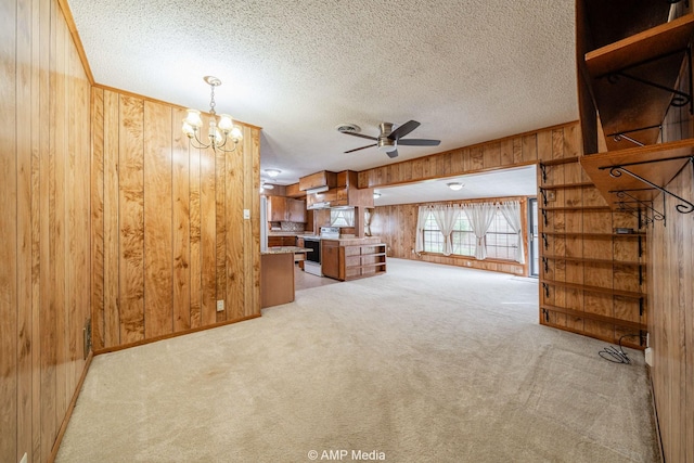2302 13th, Brownwood, TX 76801 - unfurnished living room featuring wood walls, a ceiling fan, light carpet, a chandelier, and a textured ceiling