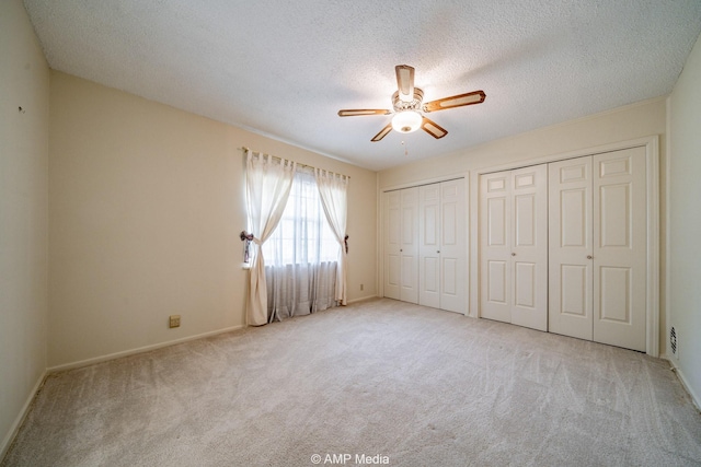2302 13th, Brownwood, TX 76801 - unfurnished bedroom with two closets, carpet flooring, a textured ceiling, baseboards, and a ceiling fan