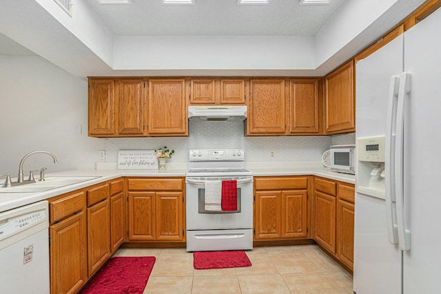 6204 Pennsylvania Ave, Arlington, TX 76017 - kitchen with white appliances, under cabinet range hood, brown cabinets, and light countertops