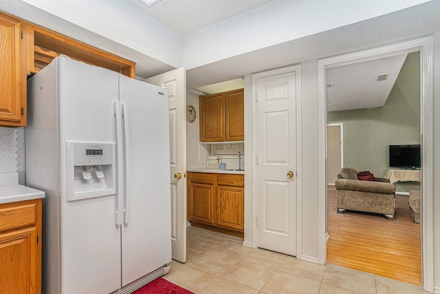6204 Pennsylvania Ave, Arlington, TX 76017 - kitchen with white refrigerator with ice dispenser, brown cabinets, and light countertops