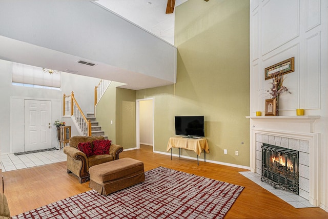 6204 Pennsylvania Ave, Arlington, TX 76017 - living area featuring wood finished floors, a high ceiling, stairs, and a tiled fireplace