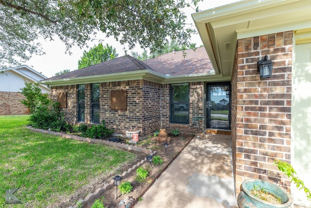 1626 Morrow Ln, Abilene, TX 79601 - view of exterior entry with brick siding, a shingled roof, a patio, and a yard