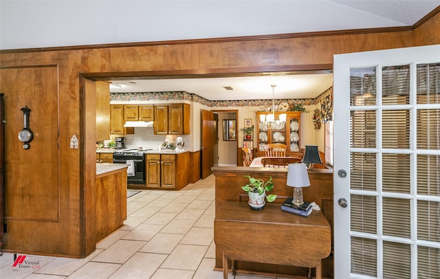 9507 Chapparral Ln, Shreveport, LA 71118 - kitchen with electric range oven, brown cabinets, a chandelier, under cabinet range hood, and light countertops