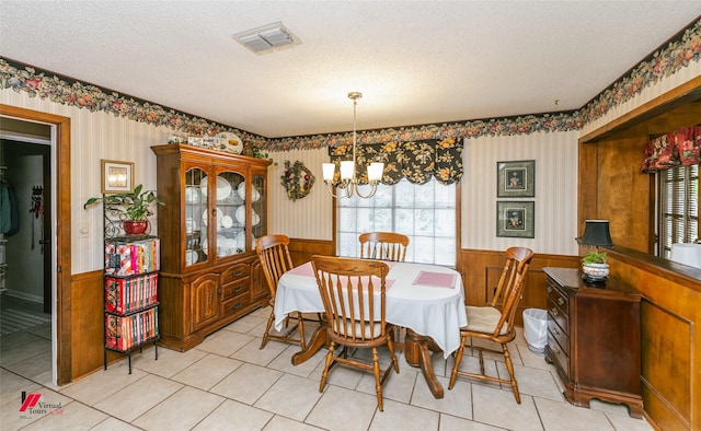 9507 Chapparral Ln, Shreveport, LA 71118 - dining room with a chandelier, a wainscoted wall, a textured ceiling, light tile patterned floors, and wallpapered walls