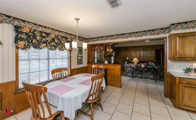 9507 Chapparral Ln, Shreveport, LA 71118 - dining room featuring a chandelier, wainscoting, a textured ceiling, wood walls, and light tile patterned floors