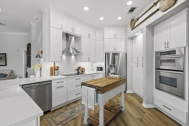 3921 Overlake Dr, Plano, TX 75023 - kitchen with stainless steel appliances, crown molding, wall chimney exhaust hood, white cabinetry, and wood finished floors