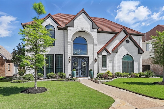 3921 Overlake Dr, Plano, TX 75023 - french country style house featuring french doors, a tile roof, a front yard, and brick siding