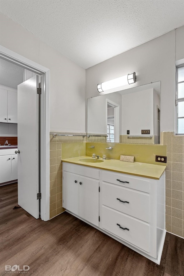 bathroom with tile walls, wood finished floors, wainscoting, vanity, and a textured ceiling
