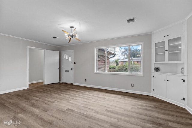 entryway with crown molding, wood finished floors, and baseboards