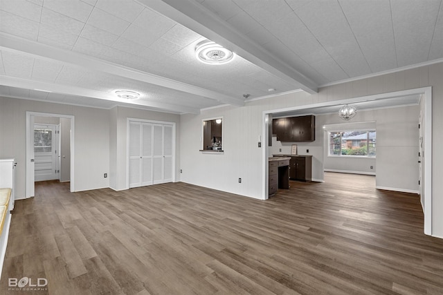 unfurnished living room featuring dark wood-style flooring, beam ceiling, ornamental molding, and a chandelier