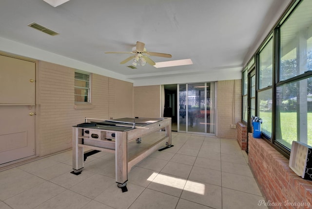 3315 Surrey Rd, Shreveport, LA 71105 - recreation room with brick wall, a ceiling fan, light tile patterned floors, and a skylight