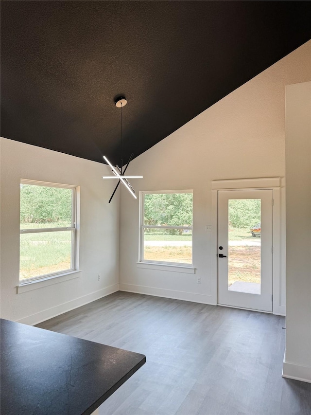 211 N 4th St, Grandview, TX 76050 - unfurnished dining area with wood finished floors, lofted ceiling, healthy amount of natural light, a chandelier, and baseboards