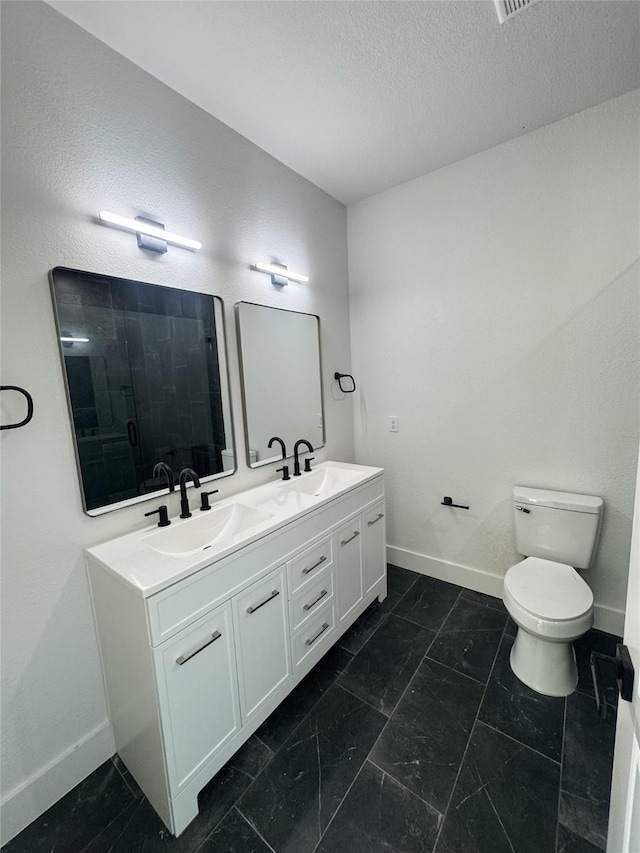 211 N 4th St, Grandview, TX 76050 - bathroom featuring baseboards, double vanity, toilet, tiled shower, and a textured ceiling