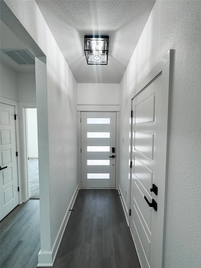 211 N 4th St, Grandview, TX 76050 - doorway to outside with dark wood-style floors, a textured wall, a textured ceiling, and baseboards