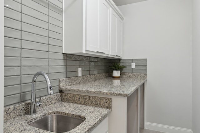 1609 Colonnade Ct, Mckinney, TX 75069 - kitchen with a sink, tasteful backsplash, white cabinetry, light stone countertops, and baseboards