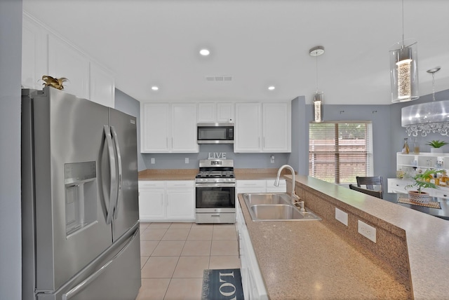 kitchen with appliances with stainless steel finishes, a sink, white cabinetry, hanging light fixtures, and recessed lighting