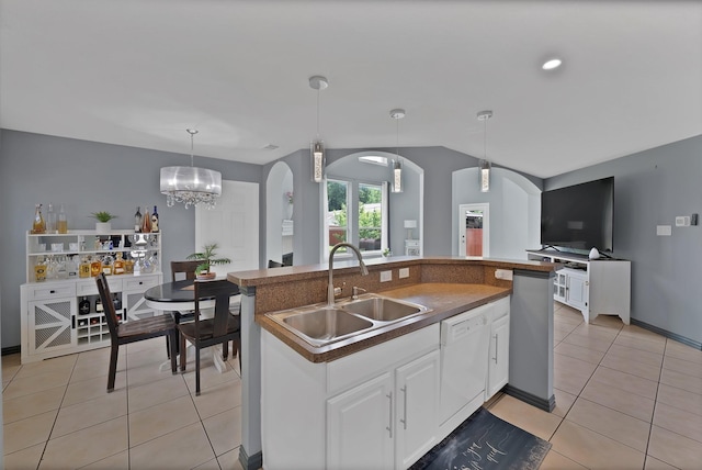 kitchen featuring a sink, white dishwasher, arched walkways, light tile patterned flooring, and white cabinetry