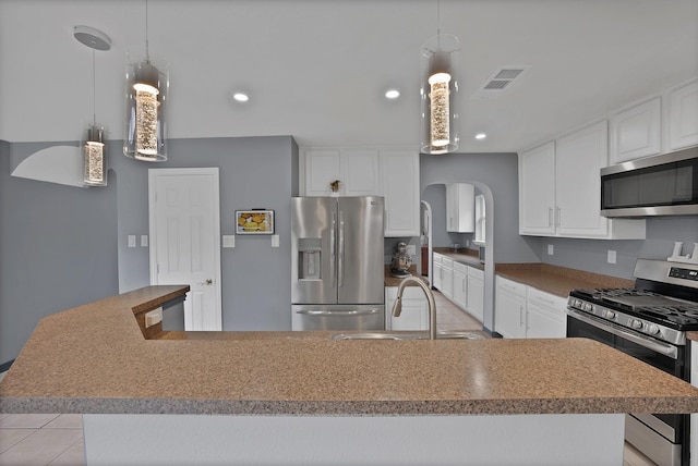 kitchen featuring stainless steel appliances, arched walkways, a sink, white cabinetry, and recessed lighting