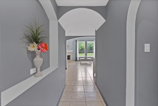 corridor featuring light tile patterned floors and arched walkways