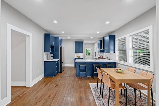 1217 Hawthorne Ave, Fort Worth, TX 76110 - kitchen featuring blue cabinetry, a peninsula, light wood-style floors, light countertops, and recessed lighting