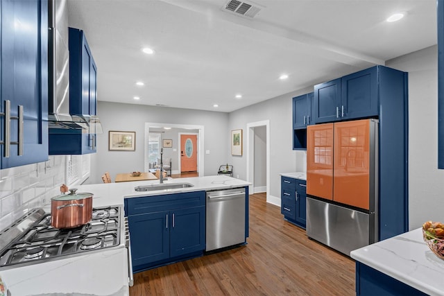 1217 Hawthorne Ave, Fort Worth, TX 76110 - kitchen with stainless steel appliances, blue cabinets, a sink, wood finished floors, and recessed lighting