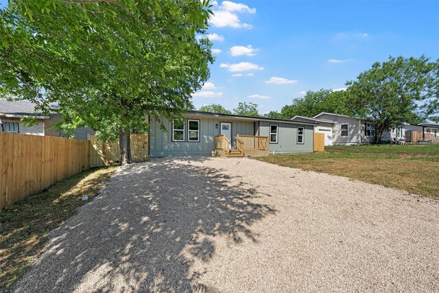 2208 Jane St, Waco, TX 76711 - view of front of house with fence, gravel driveway, and board and batten siding