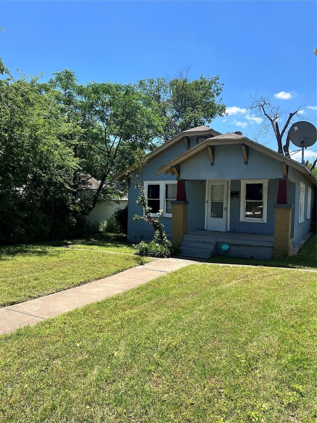 bungalow featuring covered porch and a front yard