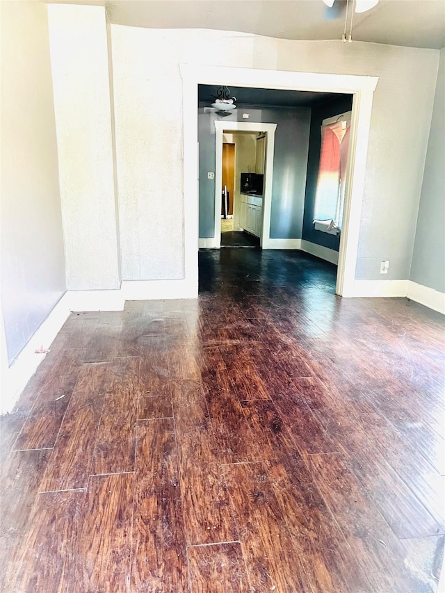unfurnished room featuring a ceiling fan, baseboards, and wood finished floors