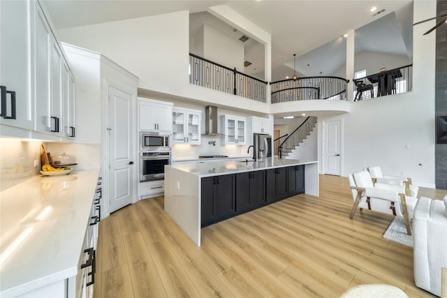 4506 Sky Harbor Dr, Rockwall, TX 75087 - kitchen with stainless steel appliances, wall chimney range hood, high vaulted ceiling, white cabinets, and light countertops