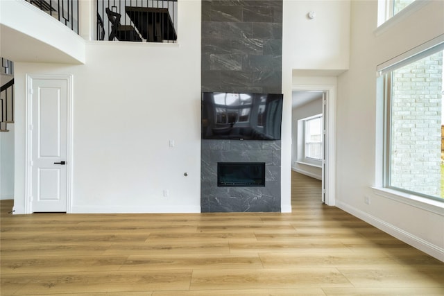 4506 Sky Harbor Dr, Rockwall, TX 75087 - unfurnished living room with a fireplace, wood finished floors, baseboards, stairs, and a towering ceiling