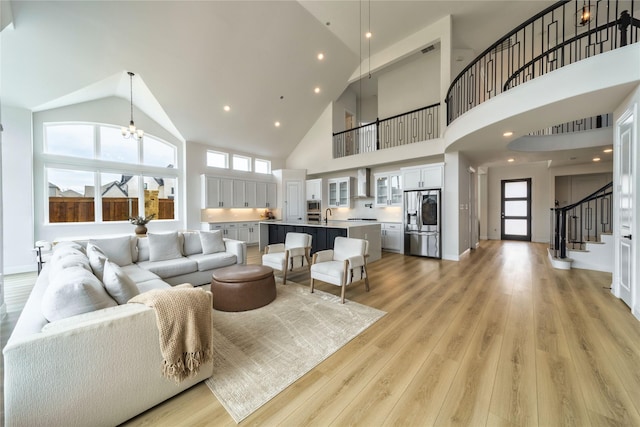 4506 Sky Harbor Dr, Rockwall, TX 75087 - living room featuring high vaulted ceiling, stairs, light wood finished floors, and a chandelier