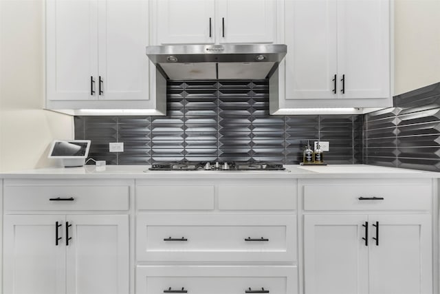 kitchen with stainless steel gas stovetop, range hood, backsplash, and white cabinets